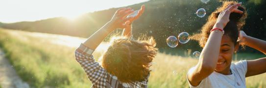 Zwei Mädchen spielen auf dem Feldweg mit Seifenblasen