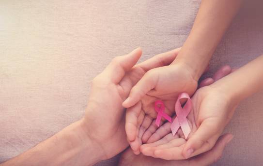 Hände von Mutter und Tochter, die rosa Schleifen halten