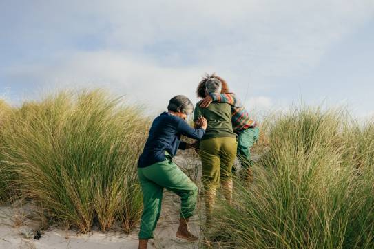 Ältere Freundinnen gehen zusammen am Strand spatzieren